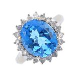 A 9ct gold topaz and diamond cluster ring. The oval-shape blue topaz, within a brilliant-cut diamond