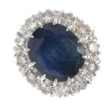 An 18ct gold sapphire and diamond cluster ring. The oval-shape sapphire, within a single-cut diamond