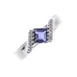 An iolite and diamond dress ring. The square-shape iolite, set at an angle between brilliant-cut