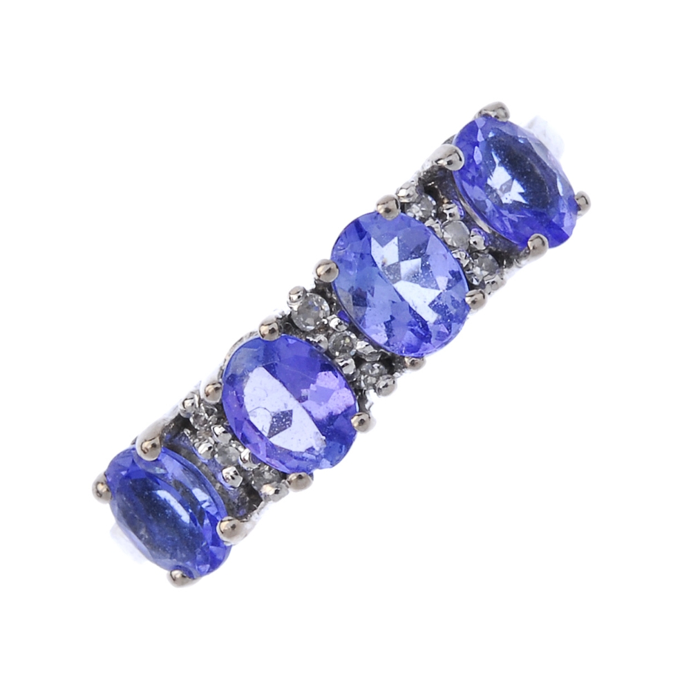 An 18ct gold tanzanite and diamond ring. The oval-shape tanzanite line, interspaced by single-cut