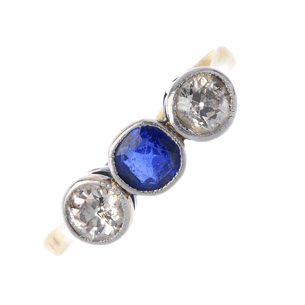 A synthetic sapphire and diamond three-stone ring. The circular-shape synthetic sapphire, with