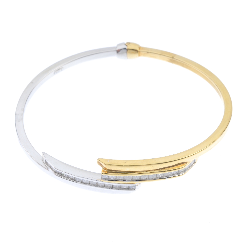 An 18ct gold diamond crossover bangle. Of asymmetric design, the square-shape diamond lines, to