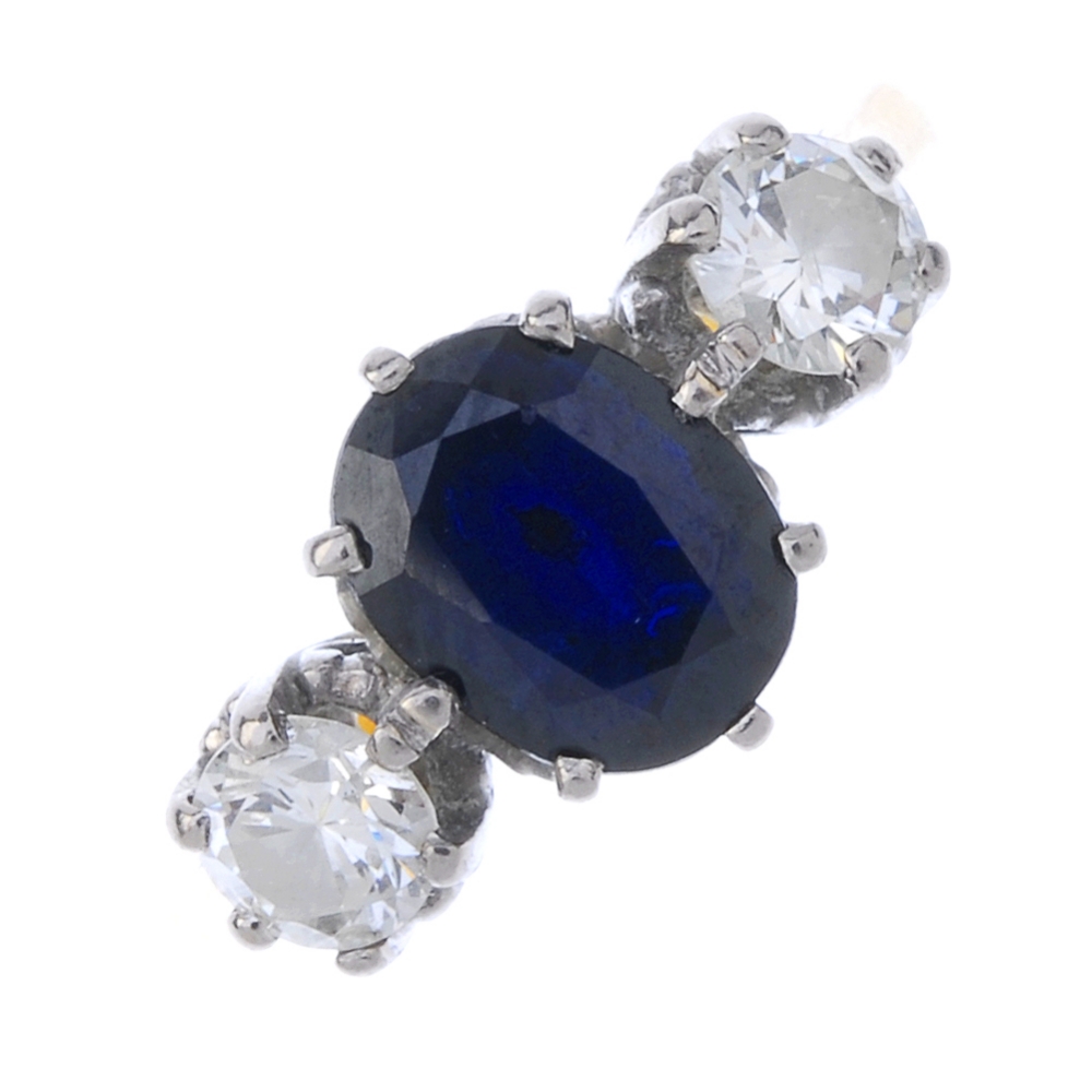 A sapphire and diamond three-stone ring. The oval-shape sapphire, with brilliant-cut diamond