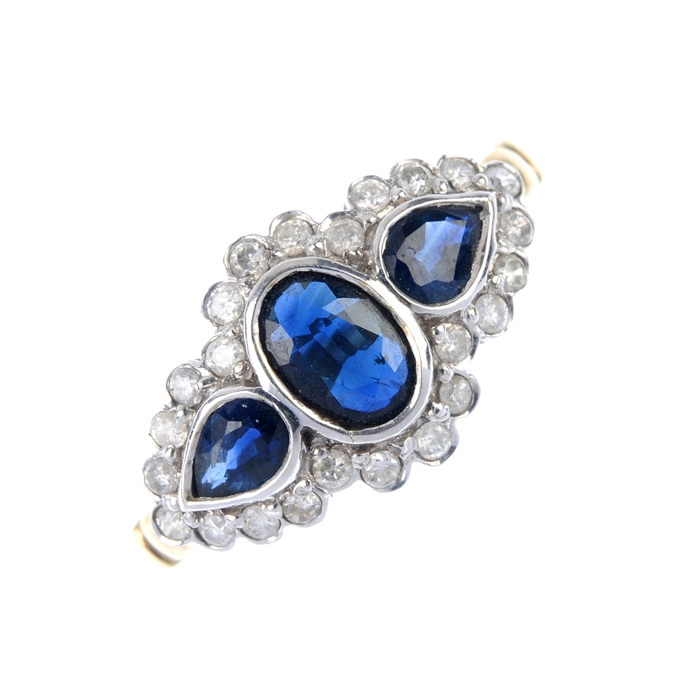An 9ct gold sapphire and diamond dress ring. The oval-shape sapphire and pear-shape sapphire
