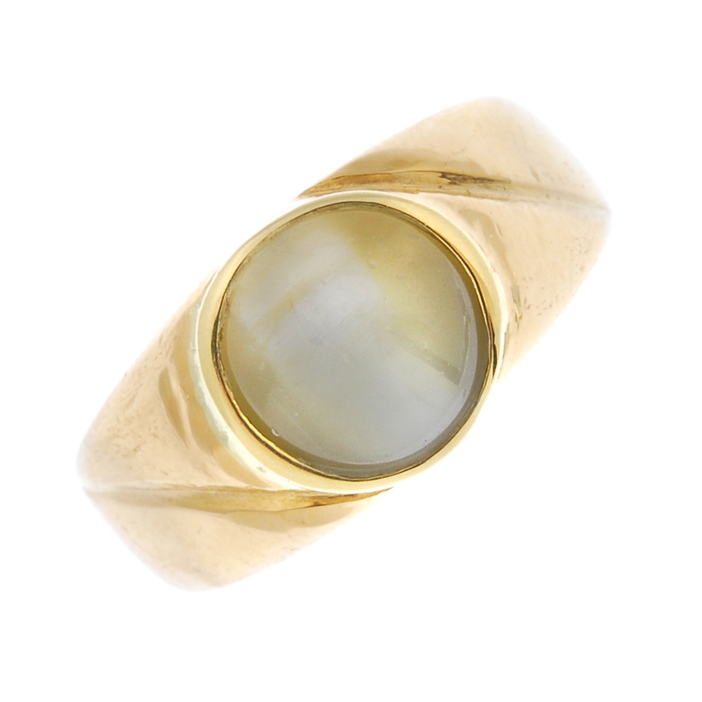 A 'cat's eye' chrysoberyl ring. The circular-shape cat's eye chrysoberyl collet, to the asymmetric