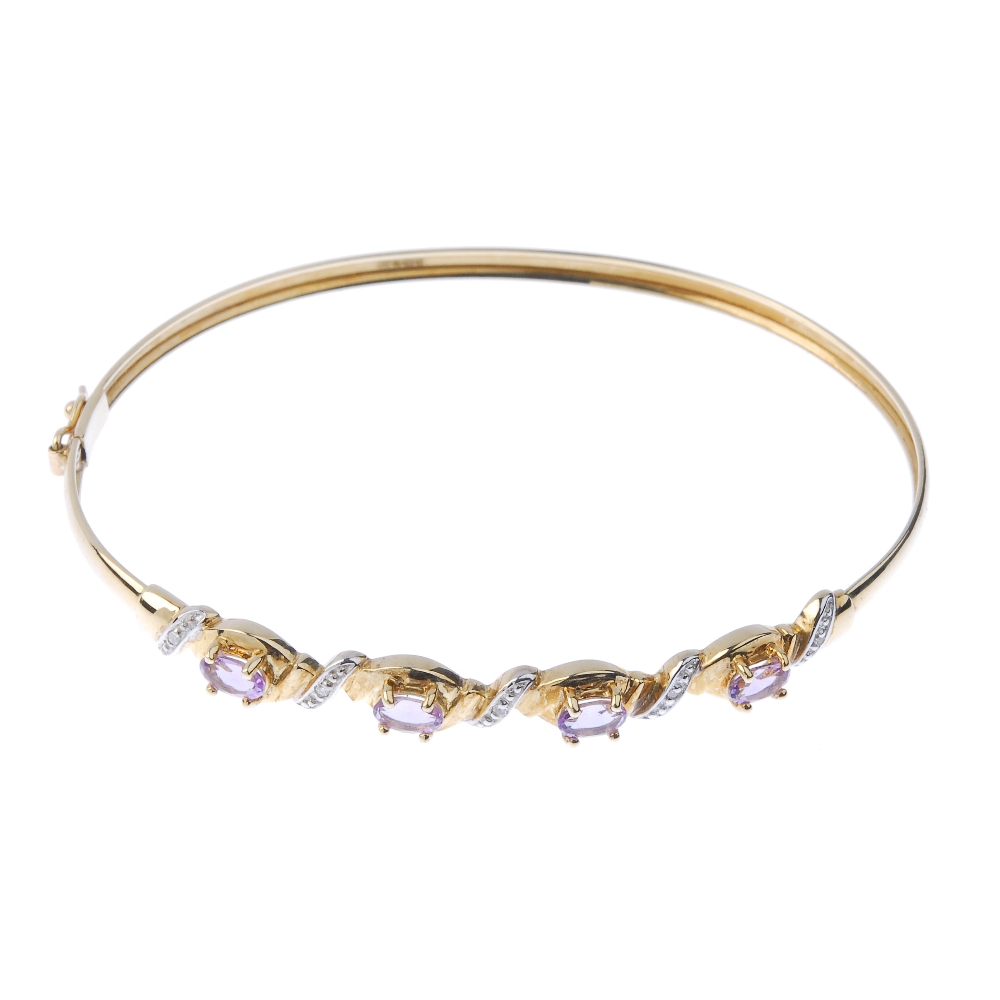 A 9ct gold diamond and amethyst bangle. The front designed as a series of oval-shape amethysts, with