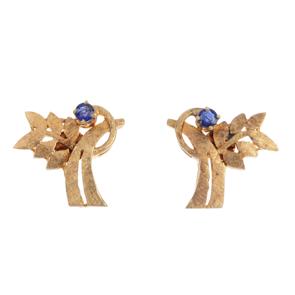 A pair of sapphire earrings. Each of foliate design, the textured branch, with circular-shape