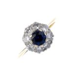 An 18ct gold sapphire and diamond cluster ring. The circular-shape sapphire, within a brilliant-