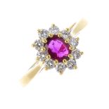 An 18ct gold ruby and diamond cluster ring. The oval-shape ruby, within a brilliant-cut diamond