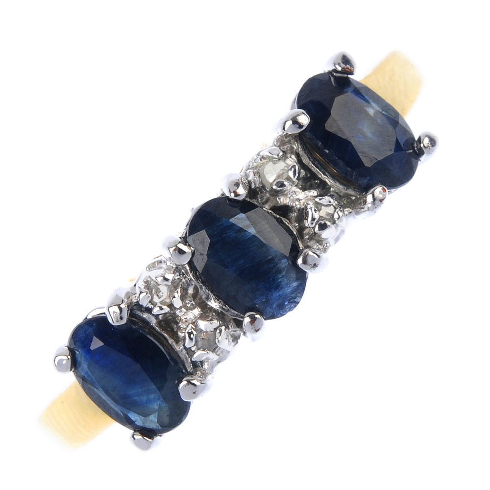 A sapphire three-stone and diamond accent ring. The oval-shape sapphire line, with diamond double