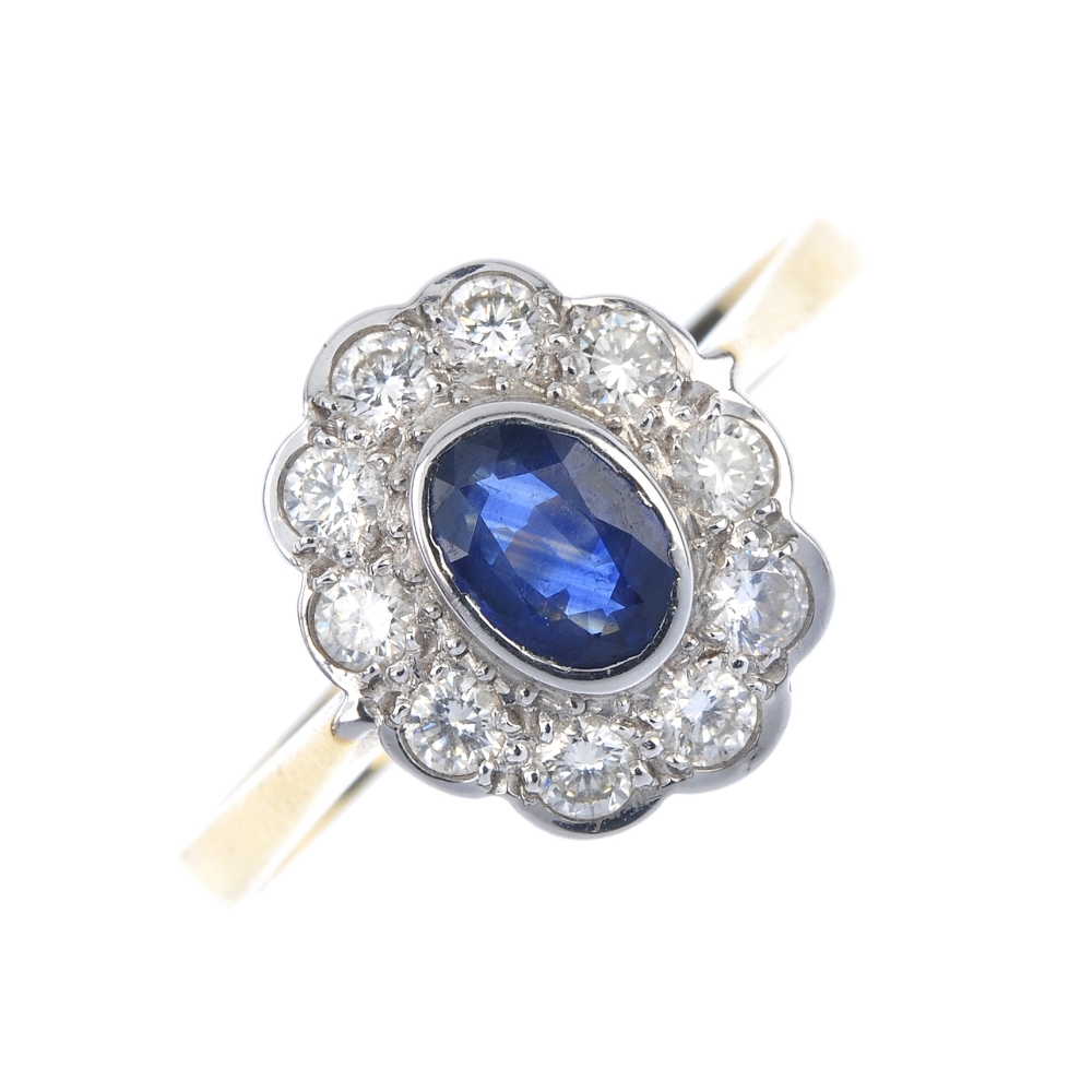 An 18ct gold sapphire and diamond cluster ring. The oval-shape sapphire, within a brilliant-cut