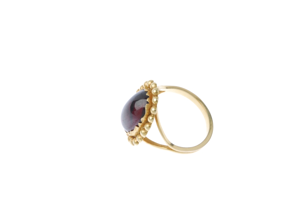 A garnet single-stone ring. The oval garnet cabochon, within a beaded surround, to the bifurcated - Image 3 of 4