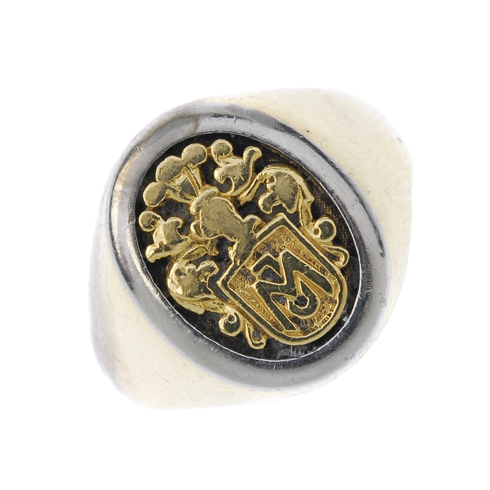 A signet ring. Of bi-colour design, the oval-shape panel, depicting a stylised armorial, to the