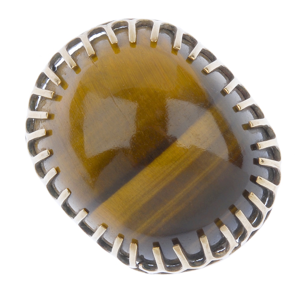 A 1970s 9ct gold tiger's eye dress ring. The cushion-shape tiger's eye cabochon, within an elongated