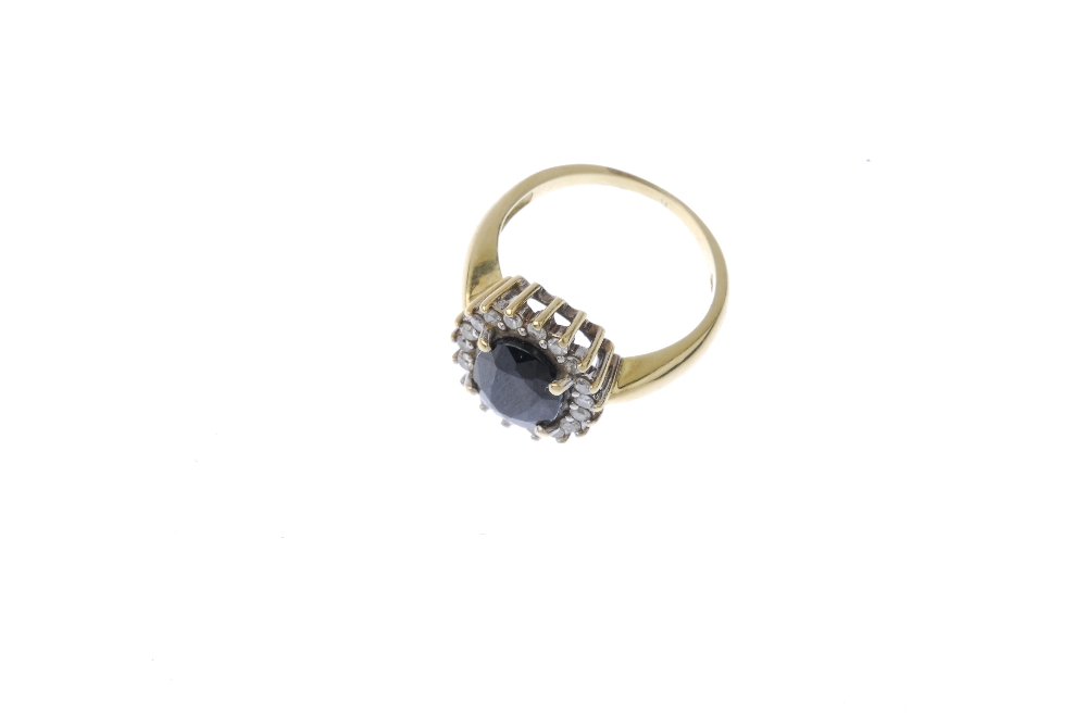 A sapphire and diamond cluster ring. The oval-shape sapphire, within a brilliant-cut diamond - Image 2 of 4