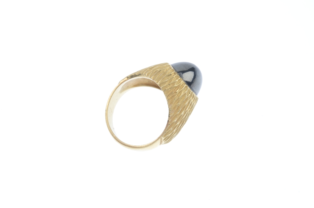 A hematite ring. The oval hematite cabochon, inset to the textured surround and plain half-band. - Image 4 of 4