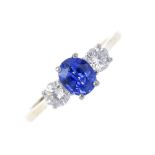 An 18ct gold sapphire and diamond three-stone ring. The oval-shape sapphire, to the brilliant-cut
