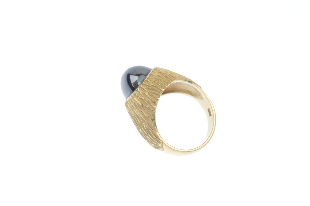 A hematite ring. The oval hematite cabochon, inset to the textured surround and plain half-band. - Image 3 of 4