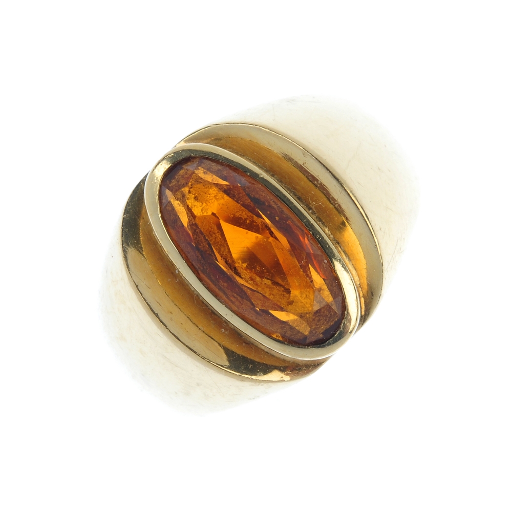 A citrine single-stone ring. The oval-shape citrine, to the tapered shoulders. Weight 8.1gms.
