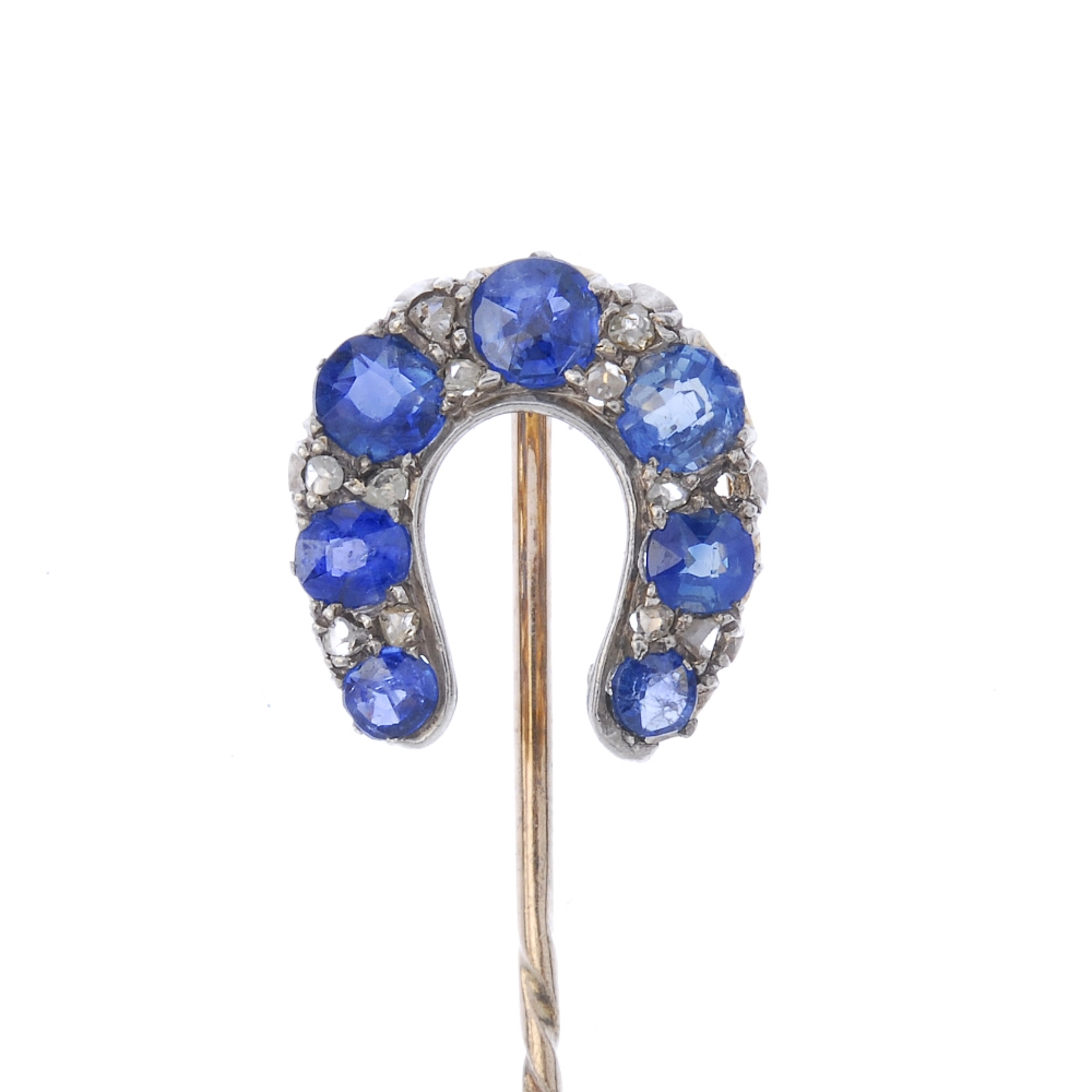 A late 19th century gold sapphire and diamond horseshoe stickpin. The circular-shape sapphire