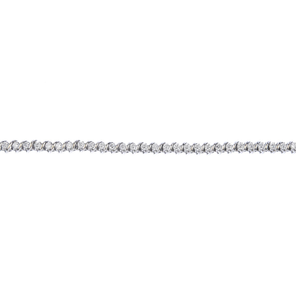 (539726-2-B) A diamond bracelet. The brilliant-cut diamond line, with scrolling spacers, to the