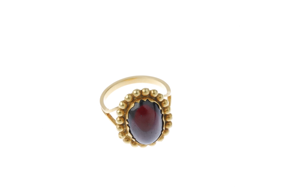 A garnet single-stone ring. The oval garnet cabochon, within a beaded surround, to the bifurcated - Image 2 of 4