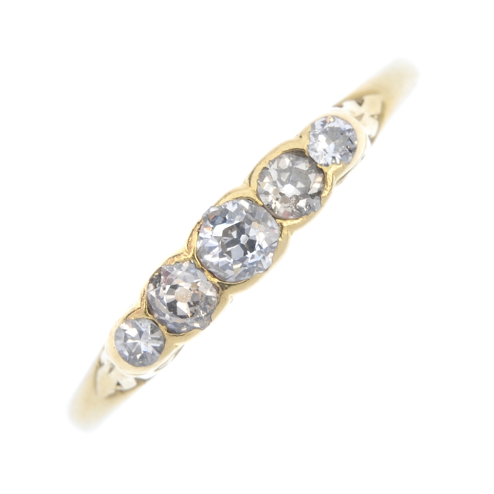 A 1920s 18ct gold diamond five-stone ring. The graduated old-cut diamonds, to the scrolling