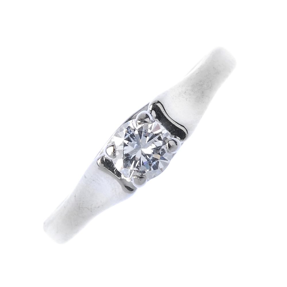 A gold diamond single-stone ring. The brilliant-cut diamond, to the wide concave shoulders and plain