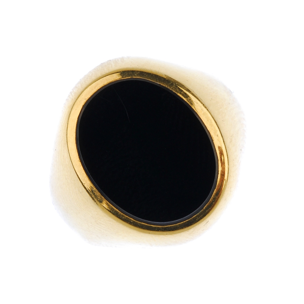 A gentleman's onyx signet ring. The oval onyx panel, to the tapered band. Weight 5.9gms. Overall