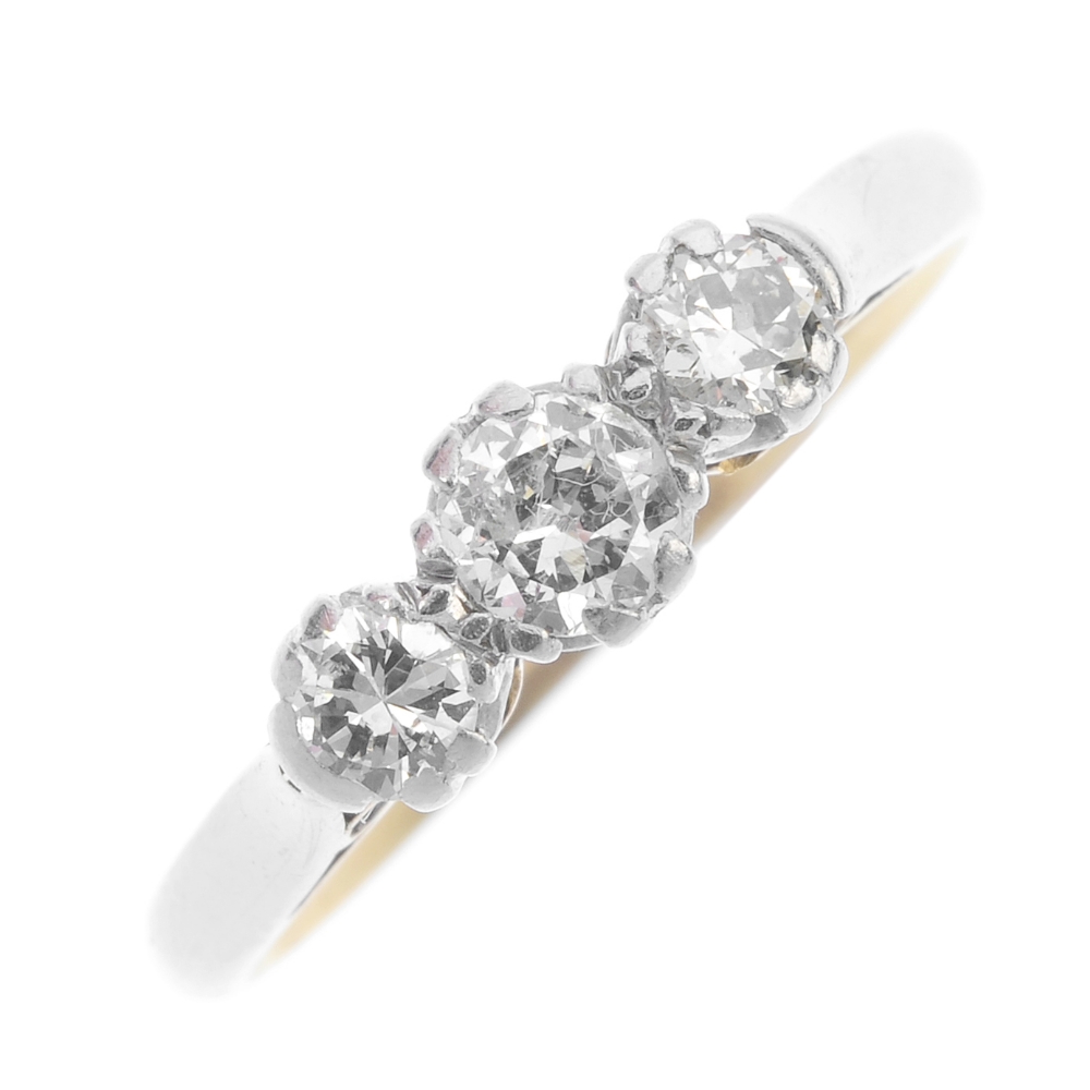 A mid 20th century gold and platinum diamond three-stone ring. The brilliant-cut diamonds, to the