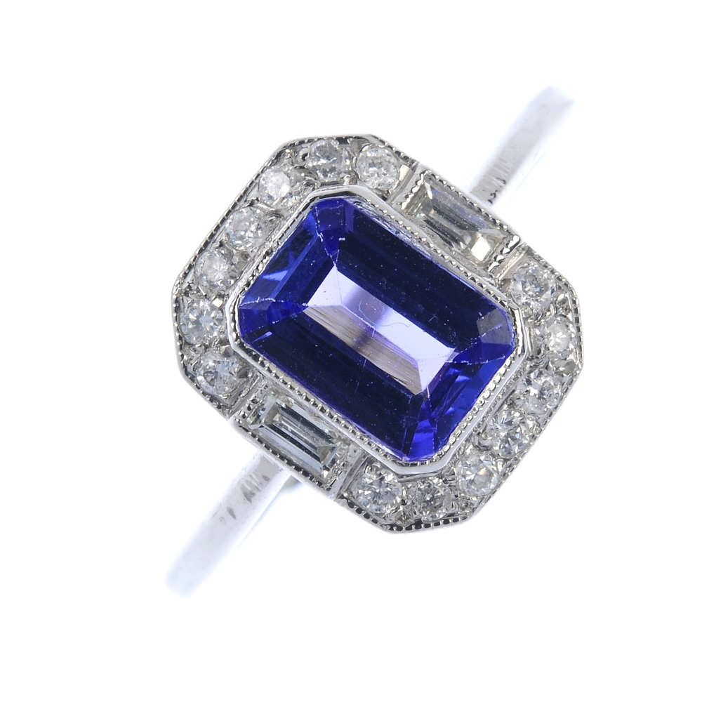 A tanzanite and diamond cluster ring. The rectangular-shape tanzanite, within a brilliant-cut