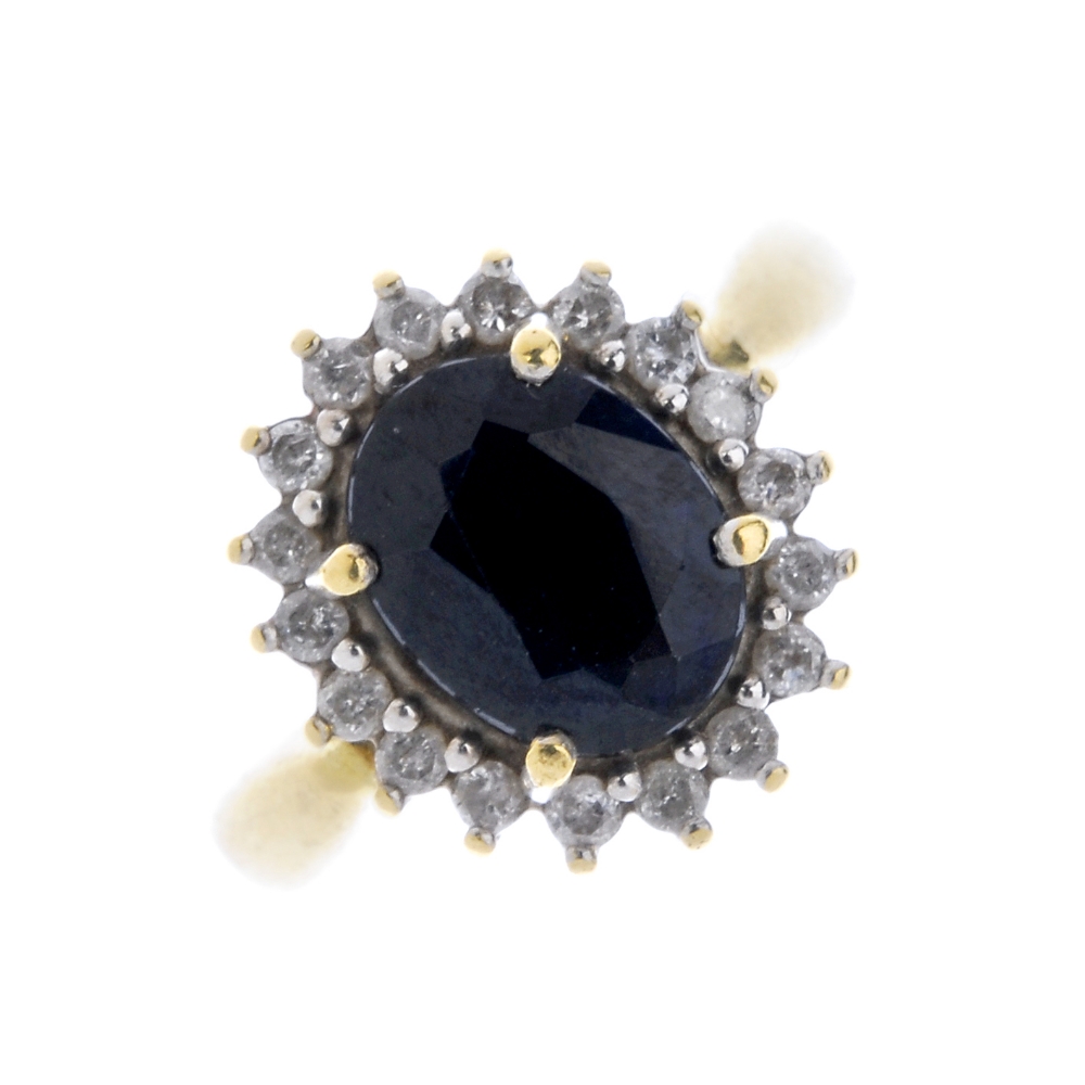 A sapphire and diamond cluster ring. The oval-shape sapphire, within a brilliant-cut diamond