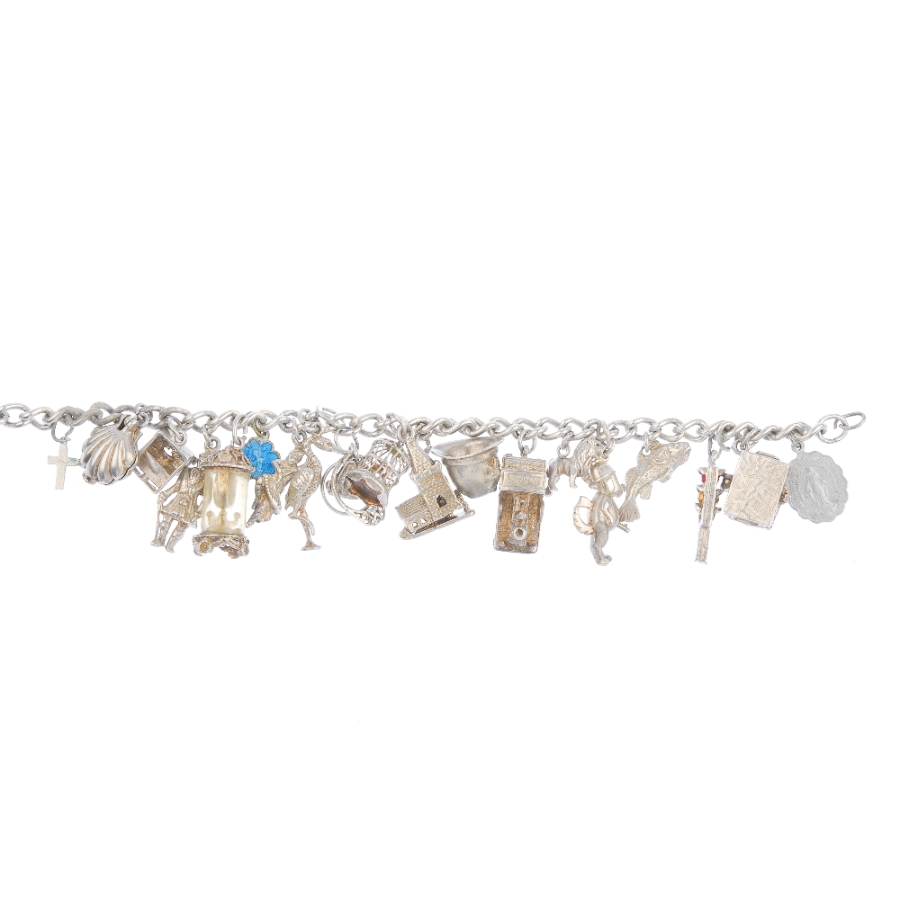 A charm bracelet. Designed as a series of nineteen charms, to include a shell and a steam train,