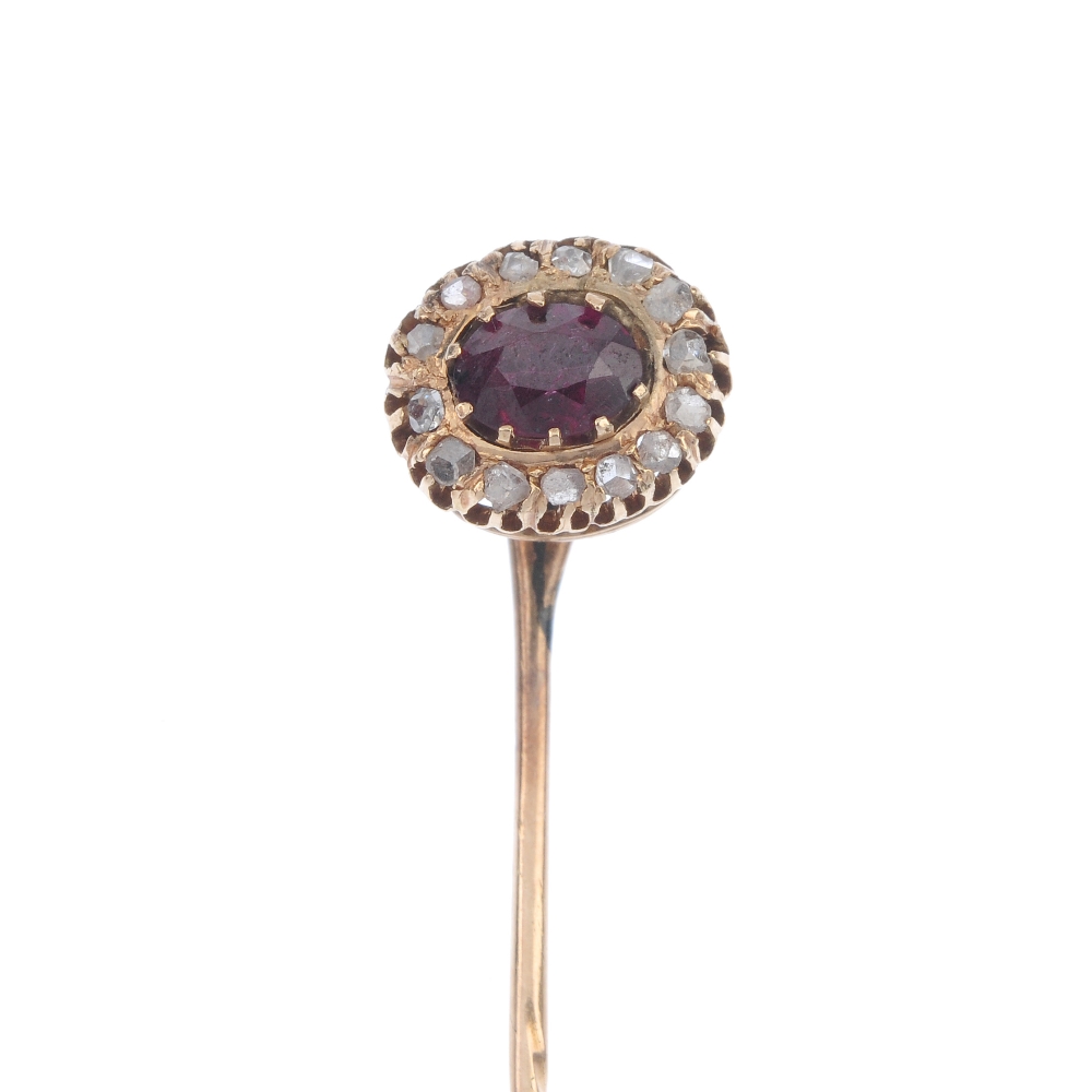 A tourmaline and diamond cluster stickpin. The oval-shape tourmaline, within a diamond point