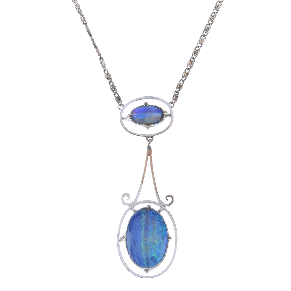 An opal pendant. Designed as an oval opal cabochon, within a halo surround, to the scrolling link,