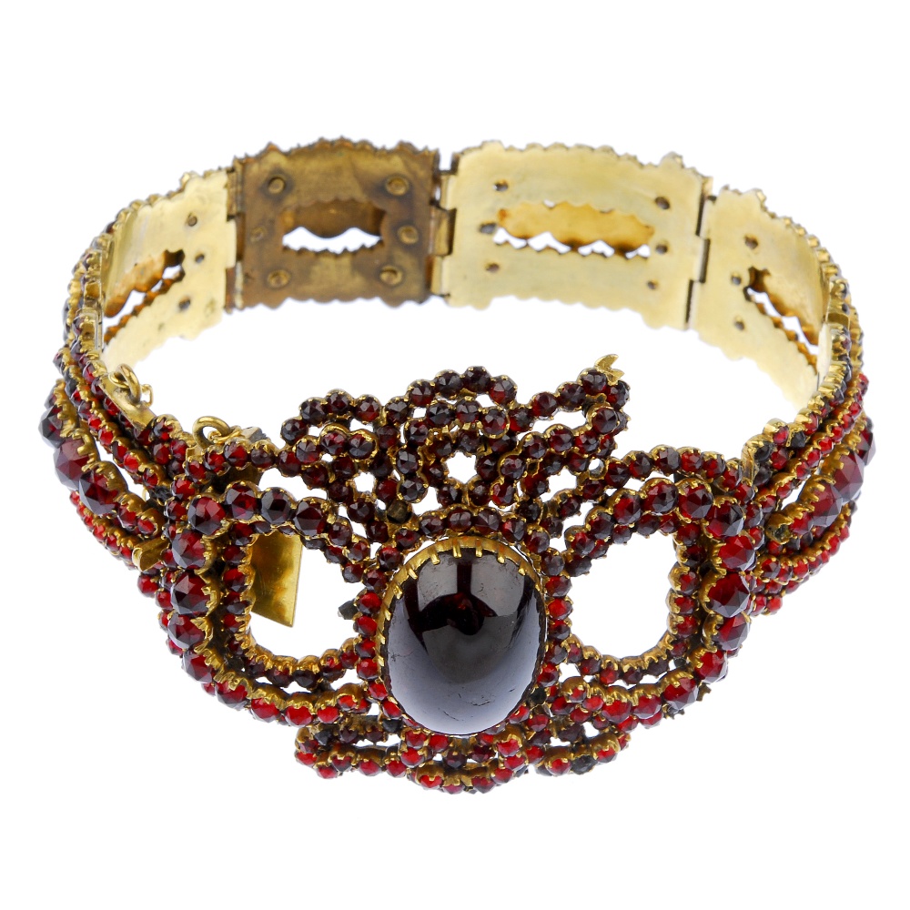 A garnet and paste bracelet. The oval garnet cabochon, within a circular-shape red paste and