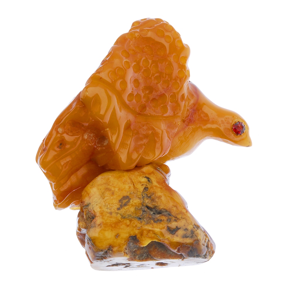 A natural amber ornament. Carved into the form of an eagle, with gem-set eyes, to the freeform