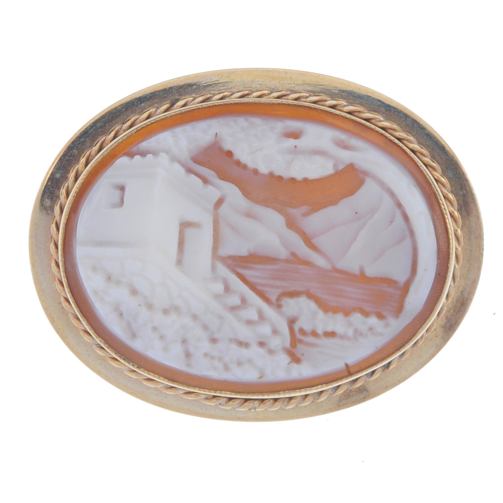 A 9ct gold cameo brooch. Of oval outline and depicting a house by a body of water. Hallmark