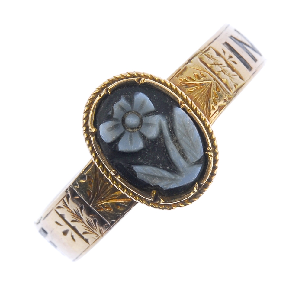 A mid Victorian gold memorial ring. The central oval onyx panel carved to depict a forget-me-not