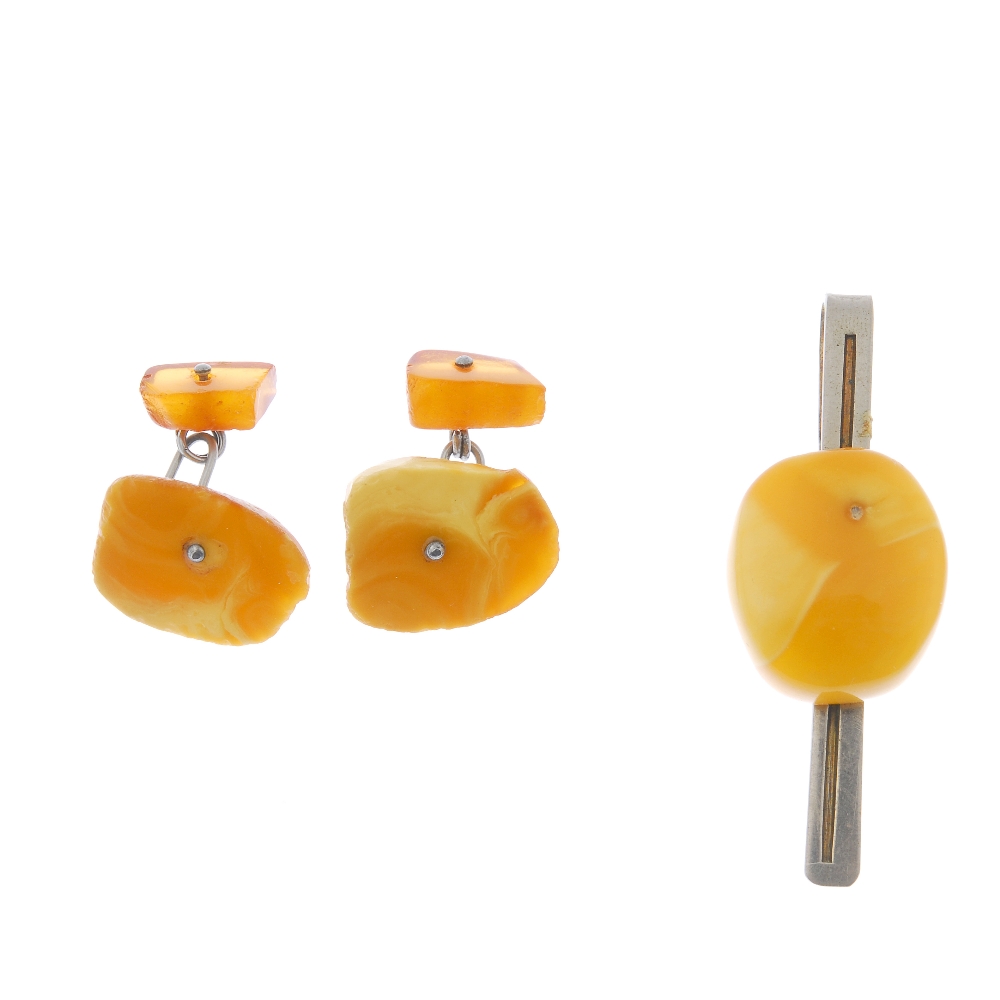 A natural amber tie slide and a pair of cufflinks. The natural amber to the tie slide, of oval
