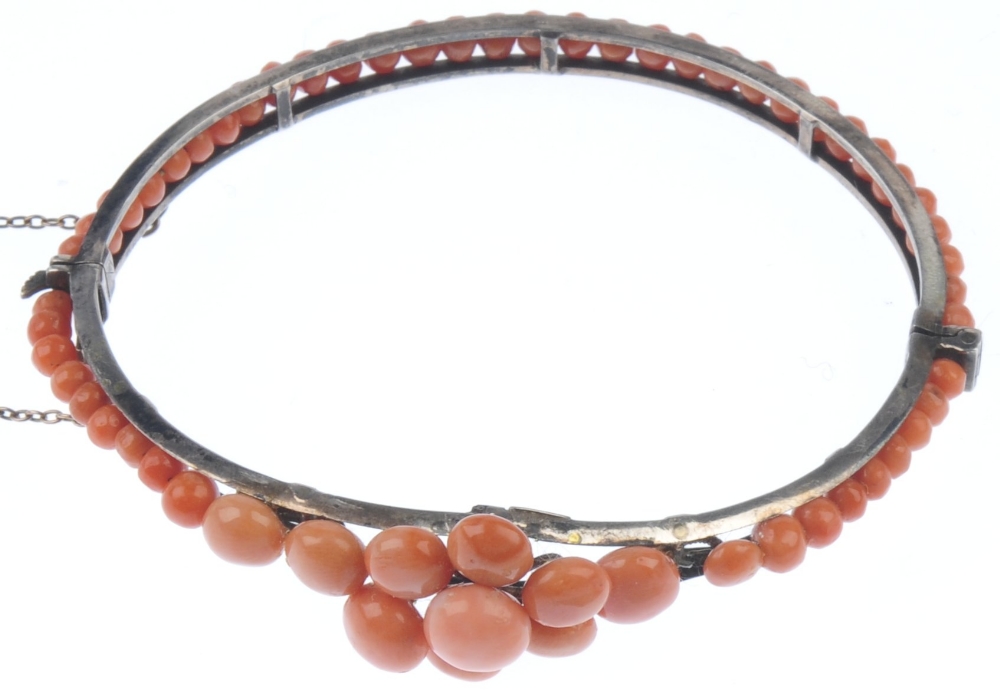 A coral bangle. Designed as a tapered front half bangle set with circular coral cabochons to the - Image 4 of 4