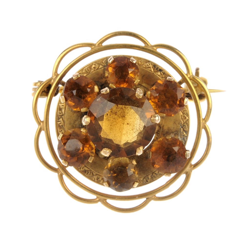 A citrine cluster brooch. The circular-shape citrine, within a similarly-cut citrine and engraved