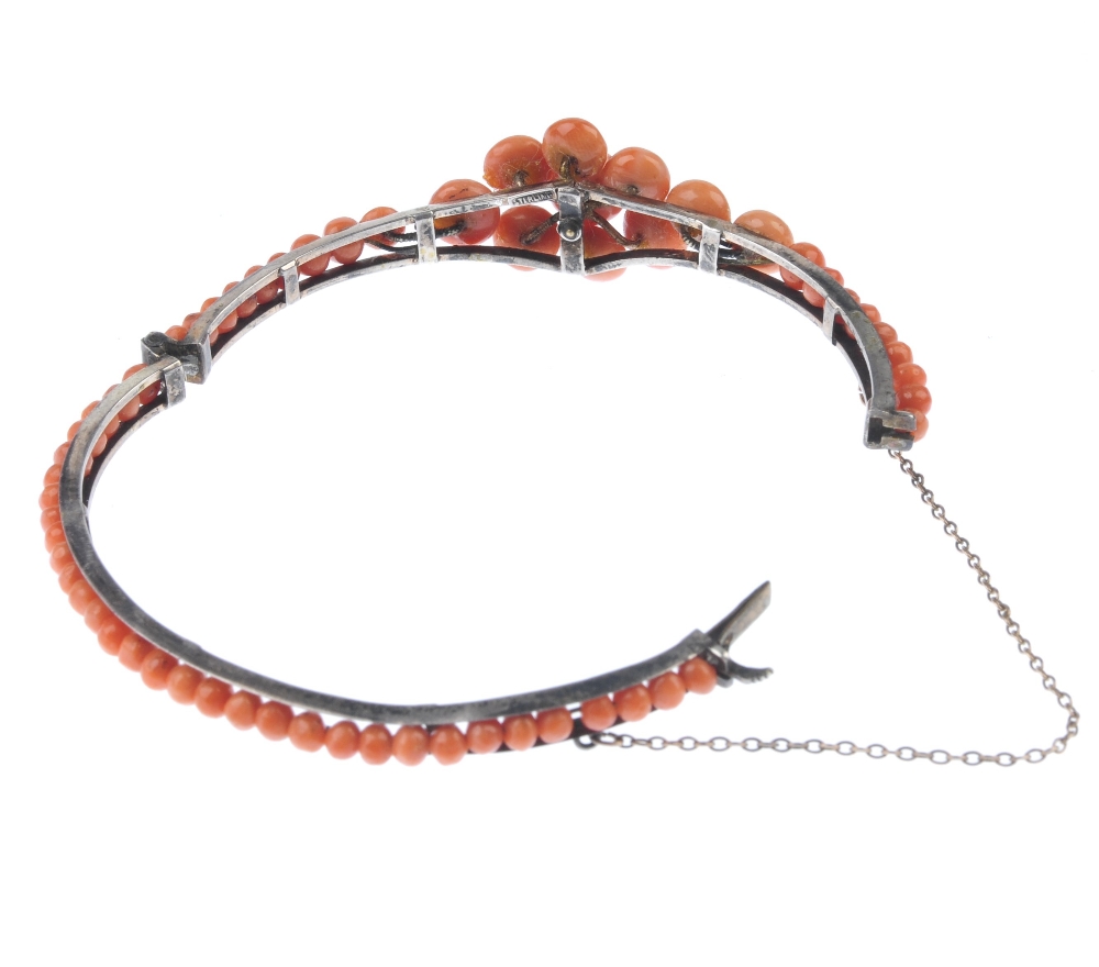 A coral bangle. Designed as a tapered front half bangle set with circular coral cabochons to the - Image 3 of 4