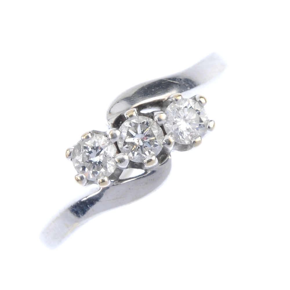 An 18ct gold diamond three-stone crossover ring. The brilliant-cut diamonds, to the asymmetric