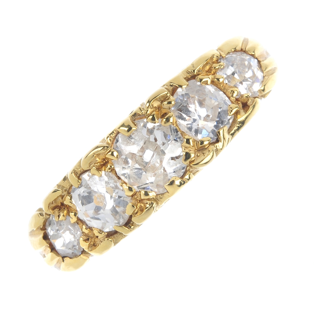 An 18ct gold diamond five-stone ring. The graduated old-cut diamond line, to the scrolling gallery