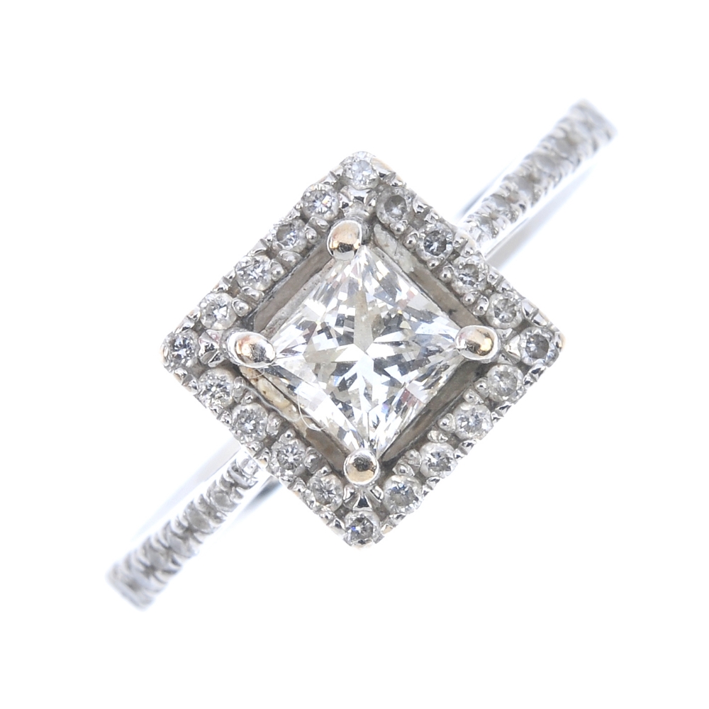 An 18ct gold diamond cluster ring. The square-shape diamond, within a brilliant-cut diamond