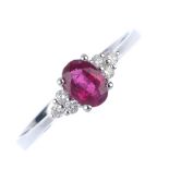 An 18ct gold ruby and diamond dress ring. The oval-shape ruby, with brilliant-cut diamond trefoil