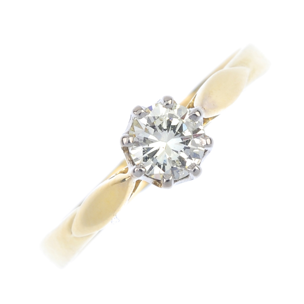 An 18ct gold diamond single-stone ring. The brilliant-cut diamond, to the foliate shoulders and
