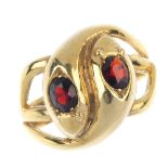 A 9ct gold garnet snake ring. Of openwork design, comprising two intertwined snakes, each with