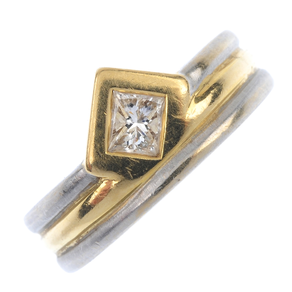 A diamond single-stone ring. The rectangular-shape diamond collet, off-set to the bi-colour